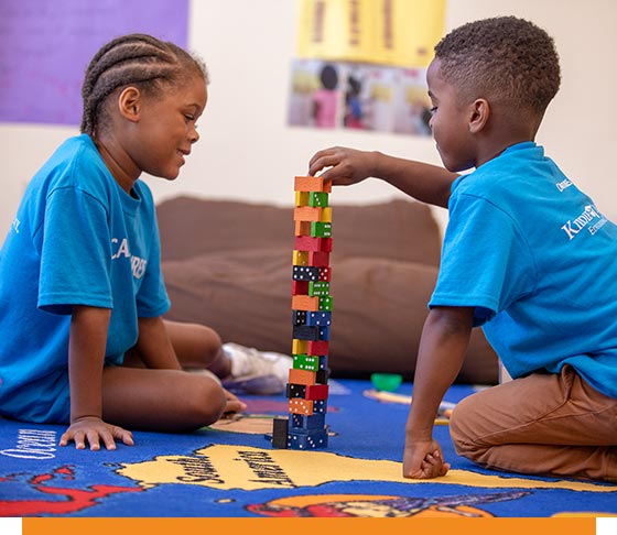 Kids play with a stack of dominos